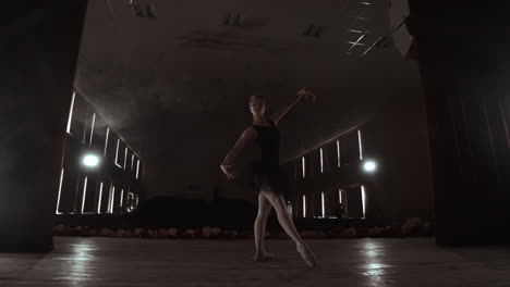 A-graceful-ballerina-dancing-ballet-elements-in-the-dark-with-light-and-smoke-on-the-background-slow-motion