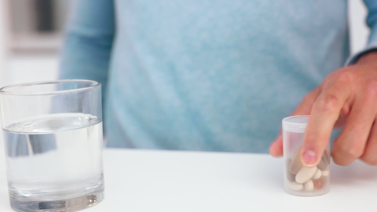 manos del hombre, agua y pastillas de medicina