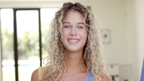 Portrait-of-happy-caucasian-woman-with-curly-blonde-hair-smiling-at-home,-slow-motion