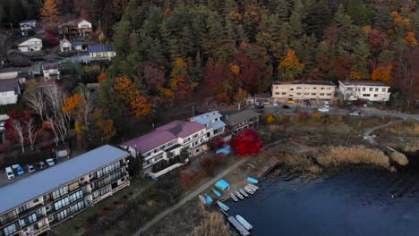 aerial pan down shot over cars driving next to autumn road and houses