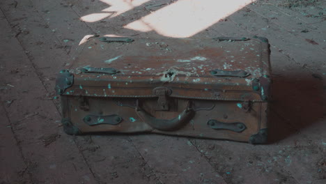 old broken rusty suitcase on dusty wooden floor