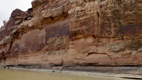 pan of sandstone canyon wall on river in utah