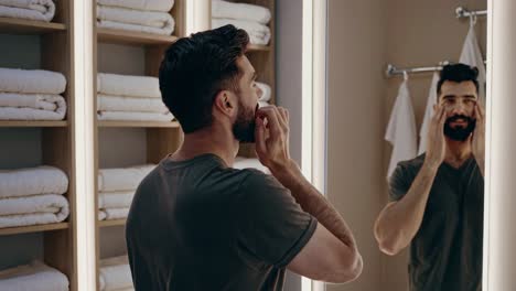 man checking his beard in the bathroom