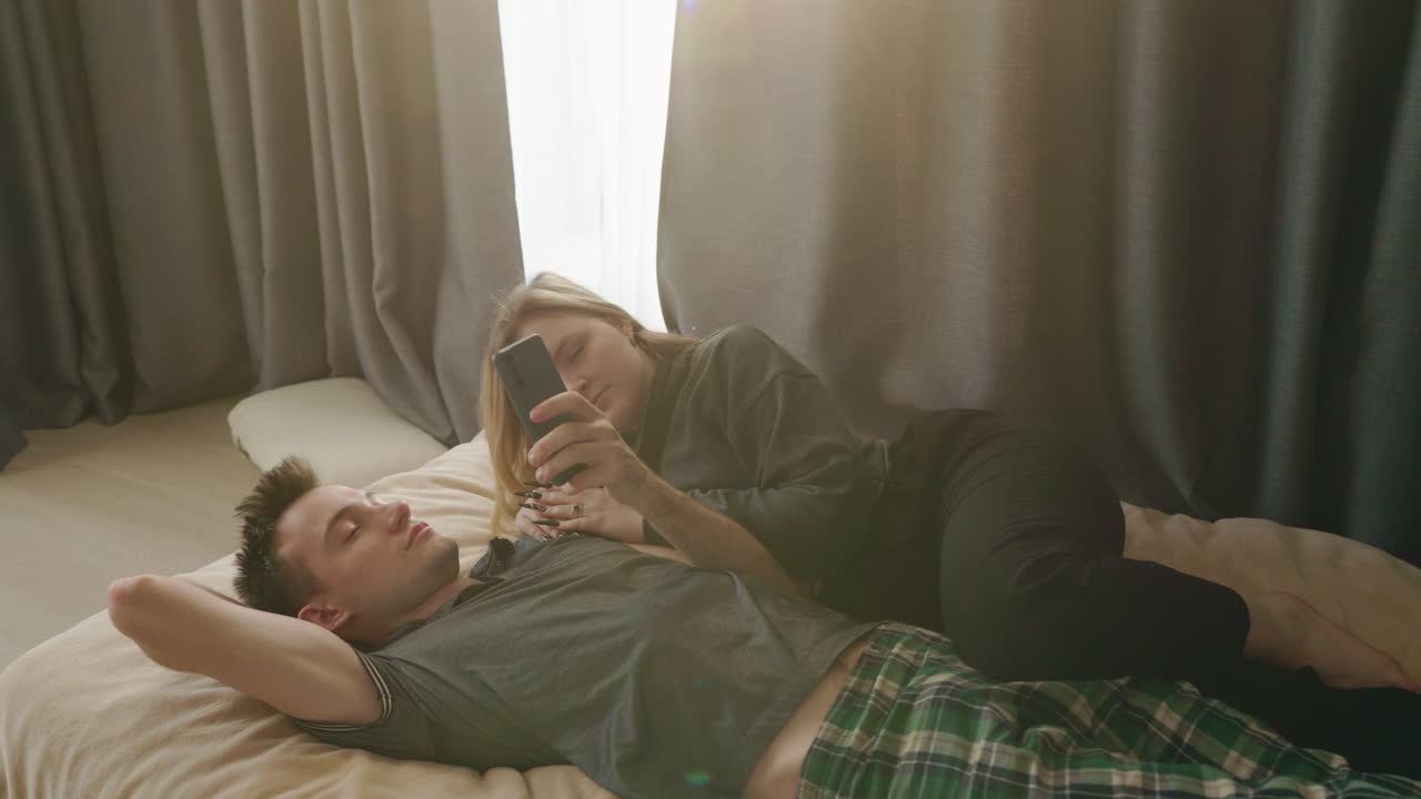 스마트폰으로 침대에서 휴식을 취하는 커플