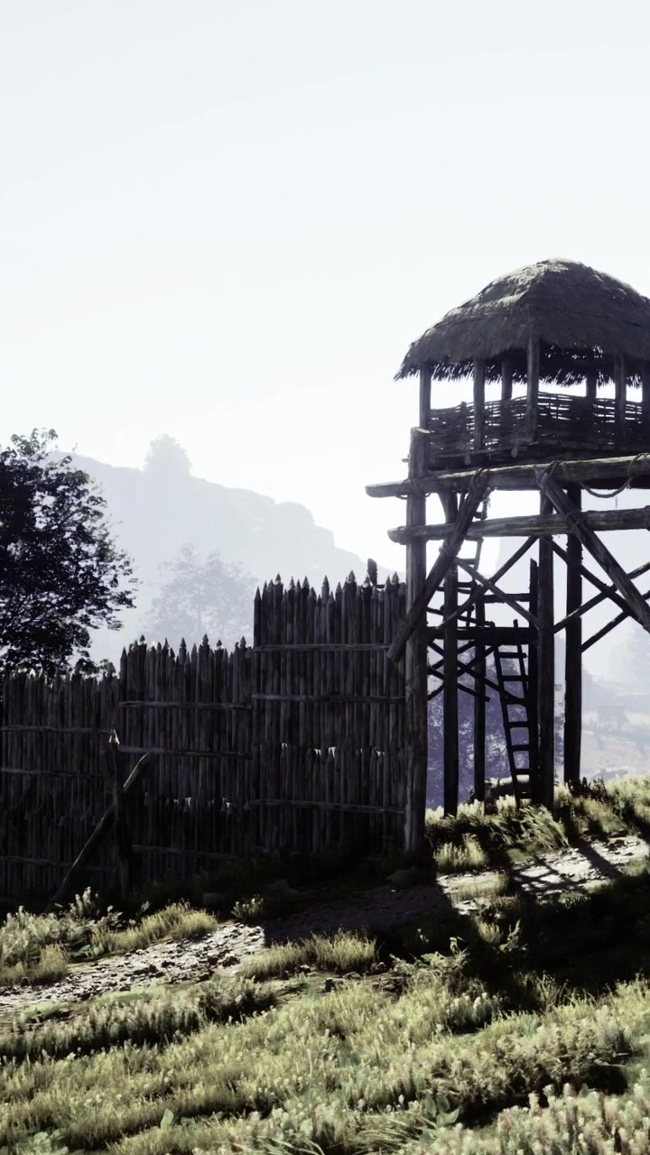 Un'alta torre di avvistamento in legno si erge accanto a una staccionata di legno in un'area rurale.