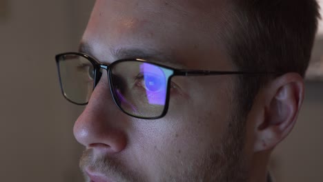 close up of man wearing blue light blocking glasses looking at screen