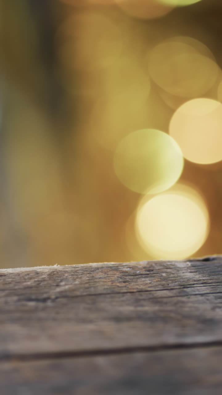 Vertical video of flickering yellow bokeh spots of light with copy space and wooden surface
