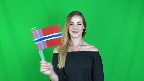 mujer rubia agitando delante de la bandera de noruega pantalla verde, fondo clave de croma