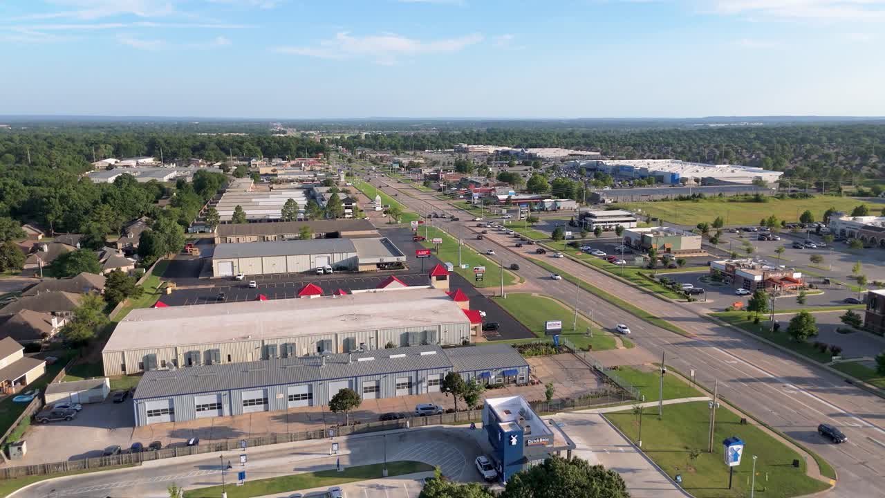 Dronebillede over en travl strækning i South Tulsa – Papa John's reklameskilt, butiksfacader og konstant trafik langs South Memorial Drive, hvor hverdagens stress møder lokal stemning