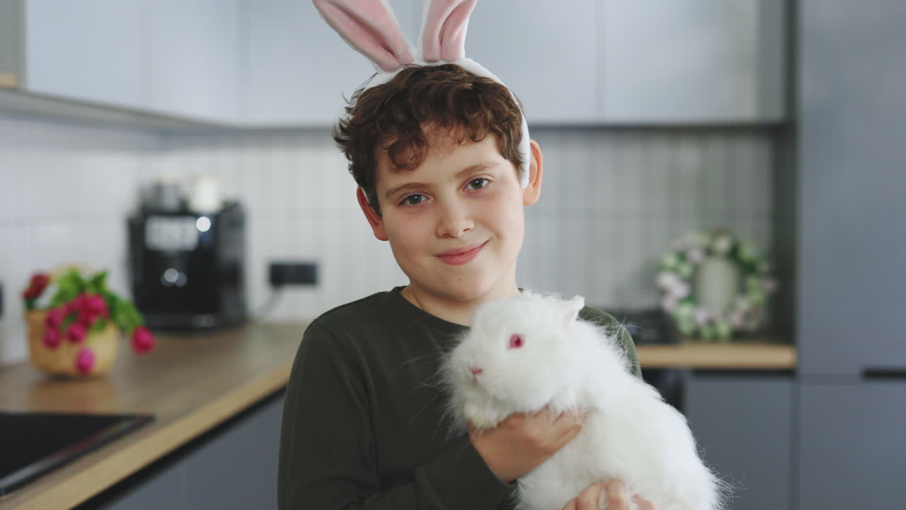 Boy with Bunny Ears and a White Rabbit in the Kitchen