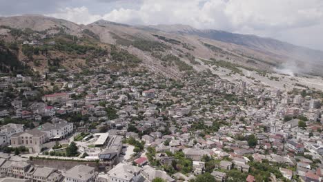 drone flyover gjirokaster paisaje urbano con enormes montañas en el fondo, albania