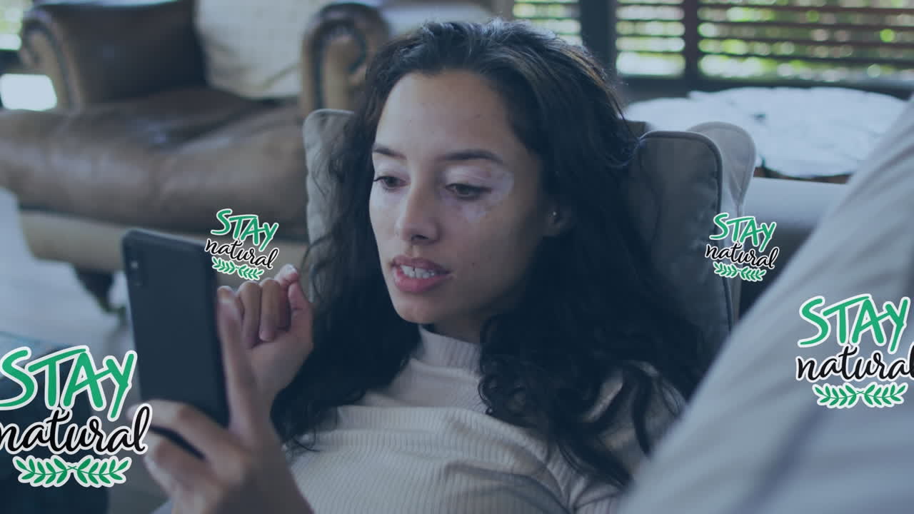 animación de permanencia natural y flores sobre mujer biracial usando teléfono inteligente