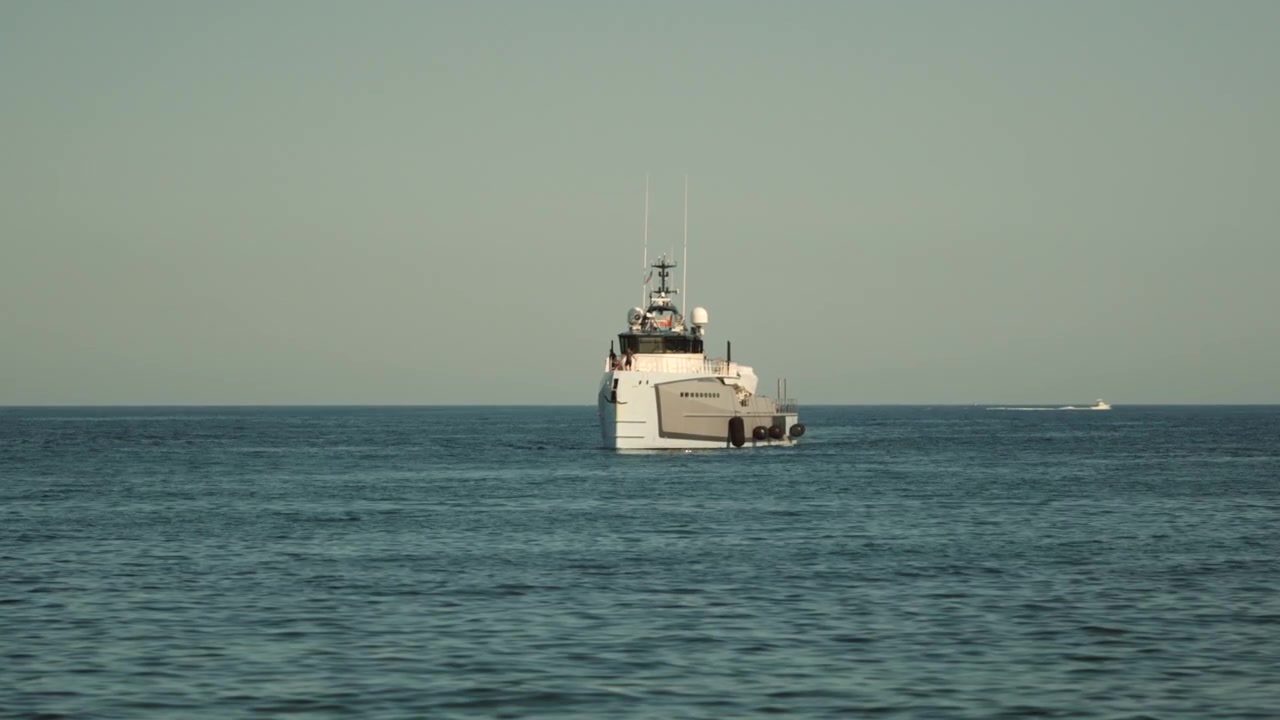 Hvidt fartøj navigerer på åbent hav på en klar dag. Koncept for rejse, udforskning, transport og maritimt eventyr.