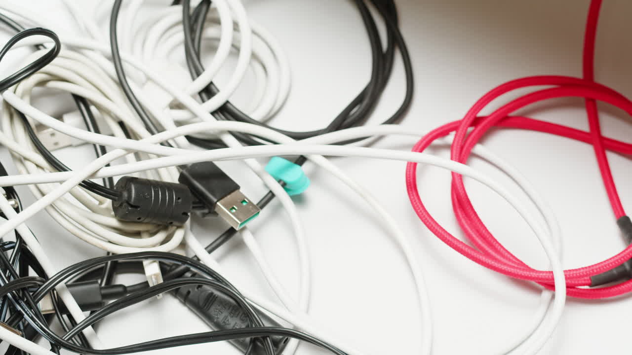 Young woman trying to untangle many various of wires close-up. Tangled wires and cables on table. Trying to untangle many messy and chaos cables