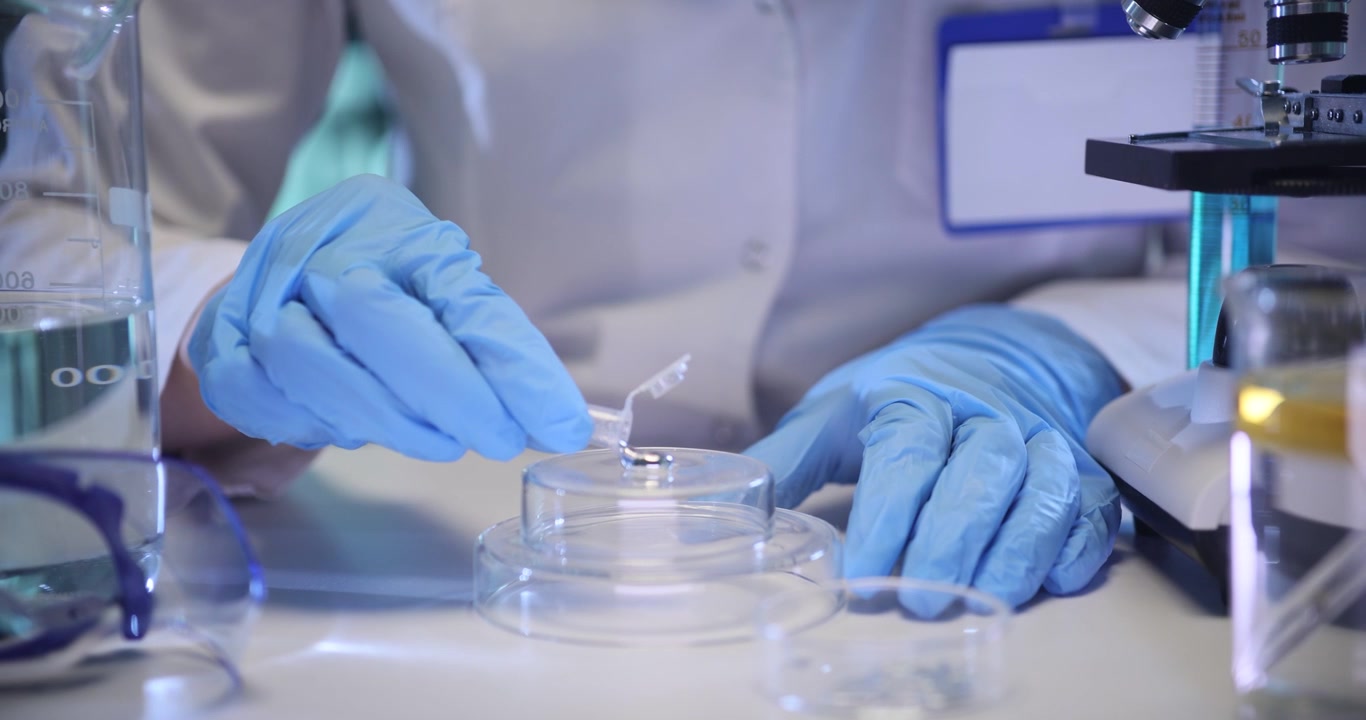 Woman scientist pours metallic liquid onto glass podium in lab