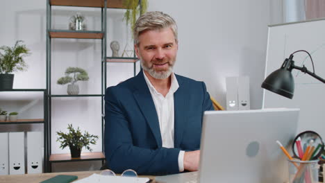 business man working on office laptop pointing to camera looking with happy expression making choice