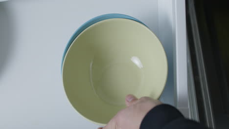 Top-shot-of-opening-a-drawer-with-a-blue-bowl,-putting-more-bowls-into-the-drawer