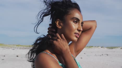 retrato de una mujer hispana relajada de pie en el sol y el viento en la playa