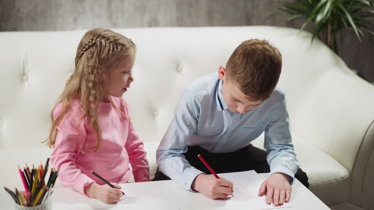мальчик пишет, сестра сидит рядом на диване и учится вместе.