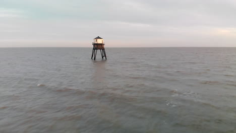 an aerial flight from the beach over one of the light houses in dovercourt, essex at sunset