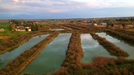 Imágenes-De-Drones-Muestran-Estanques-Artificiales-En-Una-Antigua-Fábrica-De-Azúcar,-Impresionantes-Colores-Otoñales-Y-Una-Puesta-De-Sol.