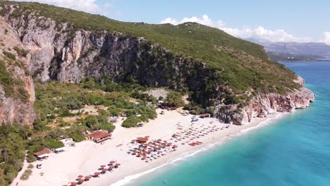 Playa-De-Gjipe,-Albania---Antena-De-Marcha-Atrás-Lenta-De-Playa-De-Arena-Blanca,-Mar-Azul-Y-Costa