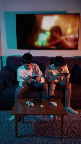 two young men playing video games on a couch