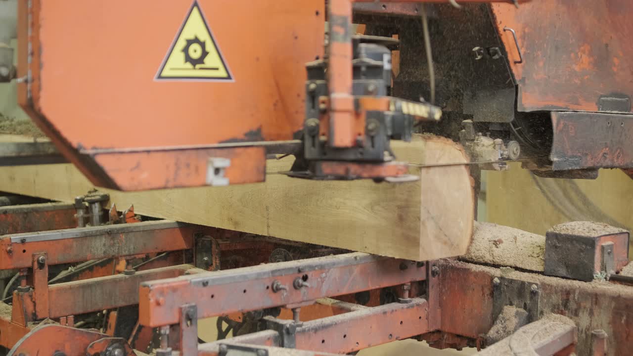 Nærbillede af en savværksmaskine, der skærer en stor træstamme