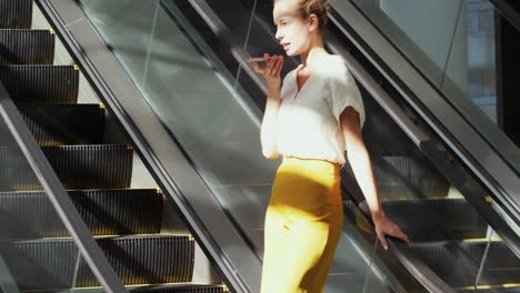 Young-businesswoman-on-an-escalator-in-a-modern-building