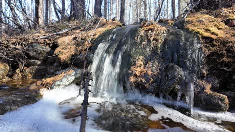 A-serene-waterfall-cascades-over-mossy-rocks-in-a-quiet-forest