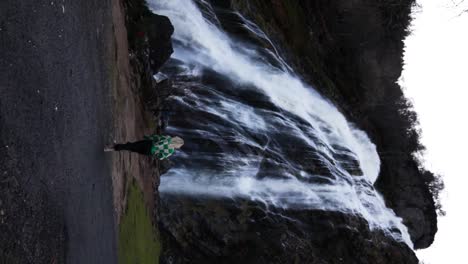 una dama rubia caminando hacia la cascada powerscourt.