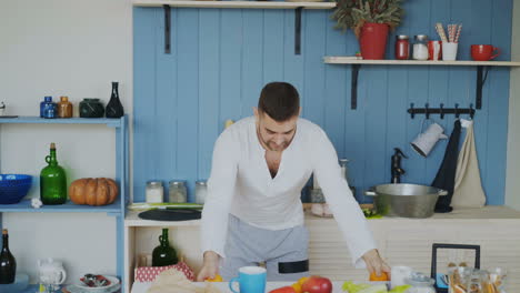 man juggling an orange in the kitchen