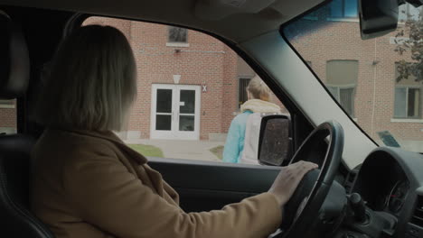 mamá desde dentro del coche parece que su hija va al edificio de la escuela. de vuelta al concepto de la escuela