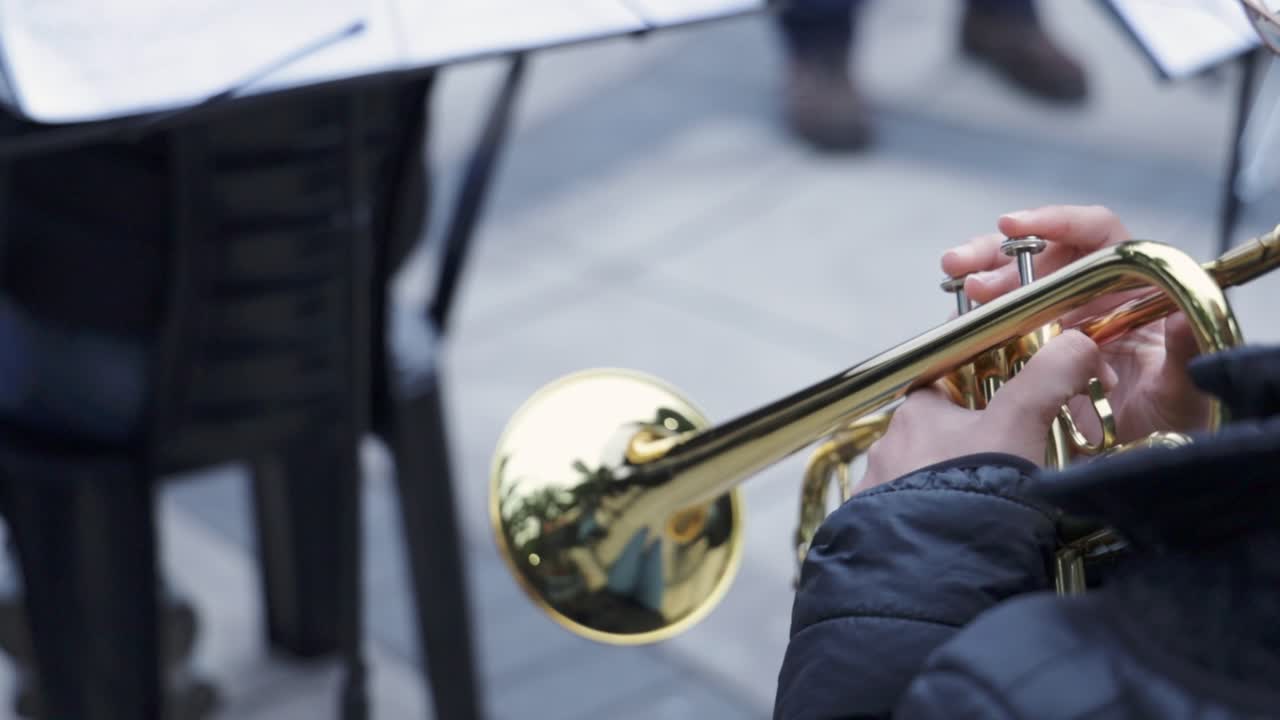 Primo piano di un musicista che suona una tromba dorata all'aperto