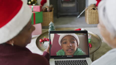 sonriendo diversas amigas mayores usando una computadora portátil para una videollamada de navidad con un niño en la pantalla