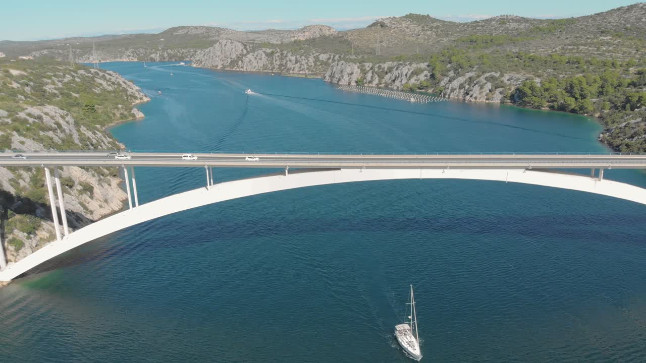 Aerial view of highway bridge over the sea ocean with car. Daily urban working traffic. Yacht sail the canal, beautiful mountain landscape