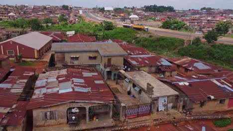 jib up of the outskirts of a larger city in ibadan, nigeria. cars drive over a highway adjacent to the slums