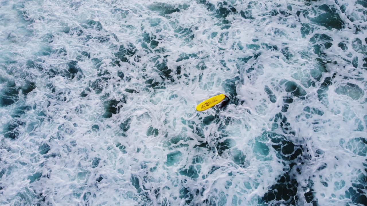一个穿着黑色潜水服的冲浪者在海上游泳,用黄色的冲浪板,等待正确的波浪 - - 空中静态射击