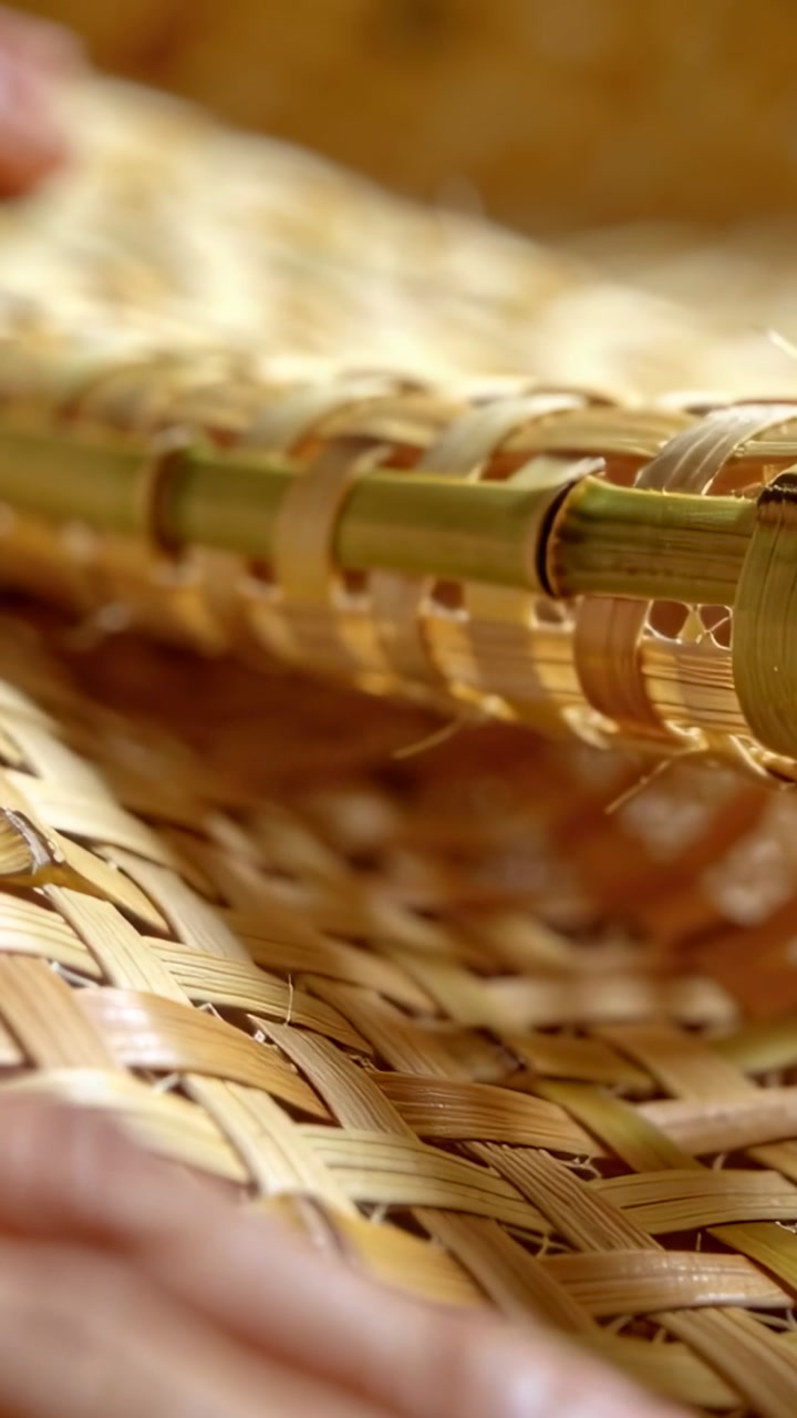 Vertical video: Lifting hand from left flexing woven rattan green rim in close-up revealing fibers
