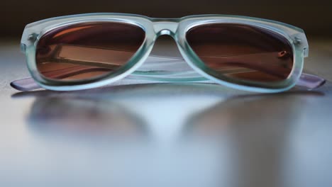 blue sunglasses sitting on slightly reflective wood table