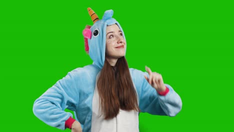 portrait of a cute young brunette girl in a beautiful unicorn costume on chrome key green background. smiling and playing. animator in costume. unicorn pajamas. 4k video with alpha channel