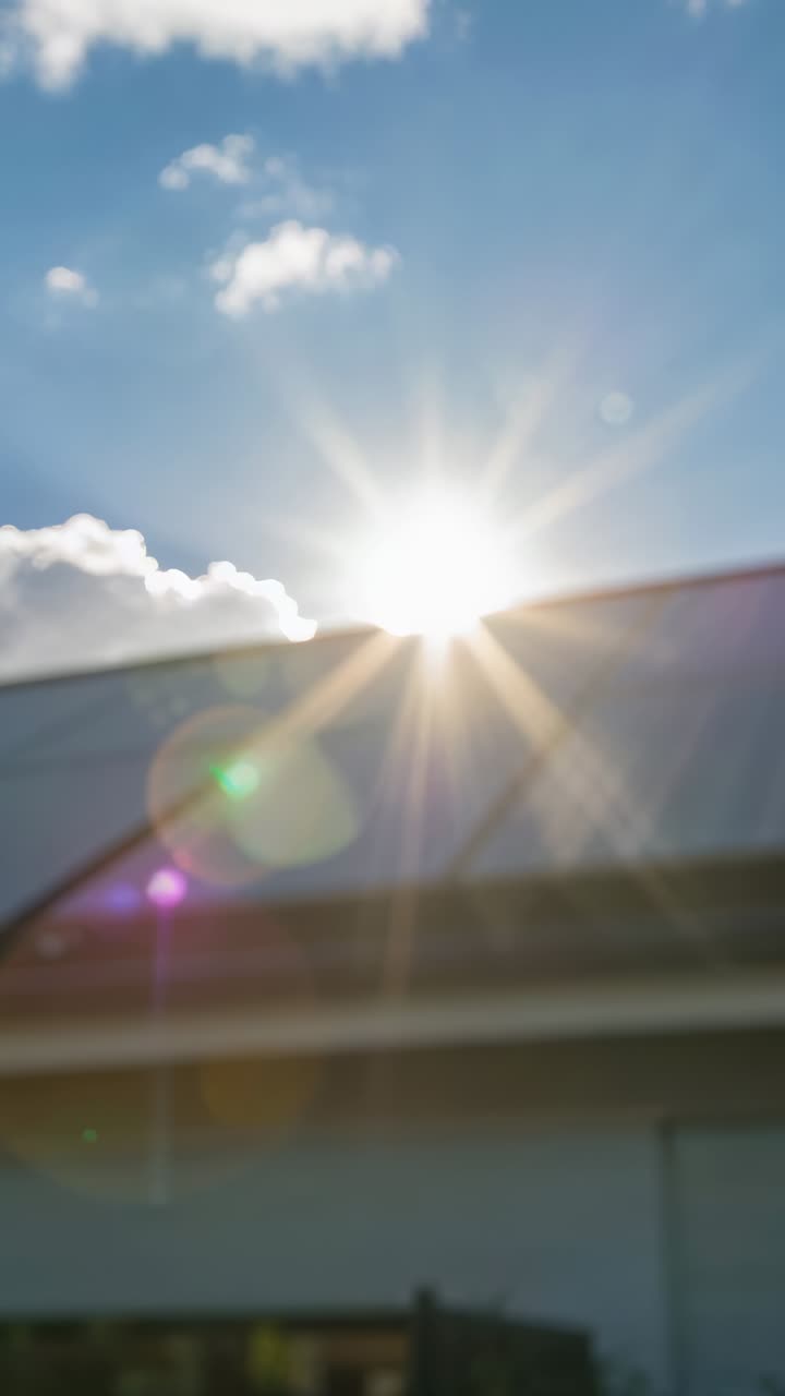 Vertical video: Peeking sun making starburst and lens flares while solar panels reflecting at home