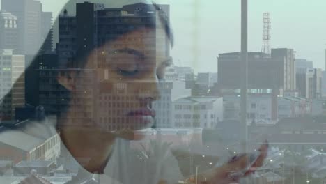 Animation-of-cityscape-over-biracial-businesswoman-using-smartphone