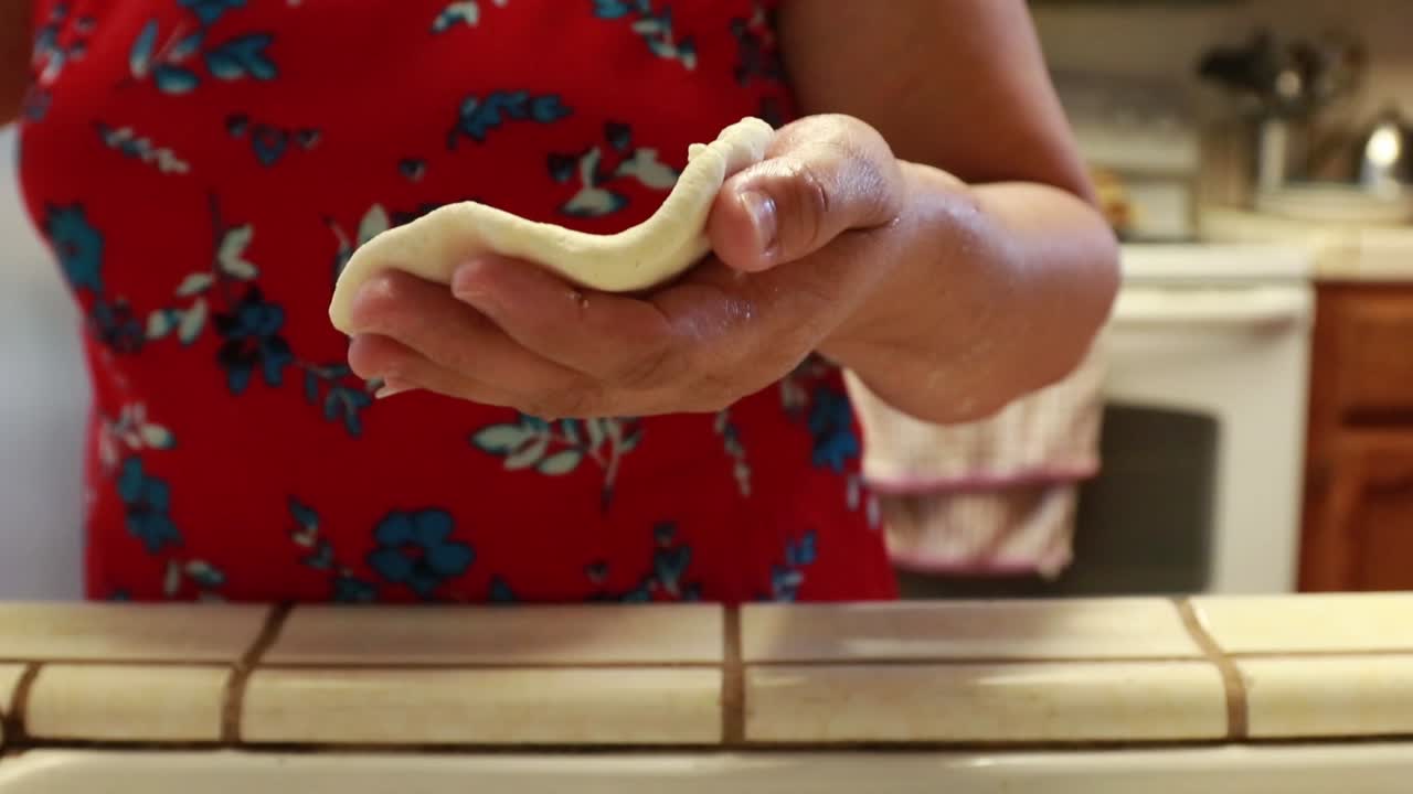 Close up of Salvadorian woman's hands as she shapes pupusas to cook.