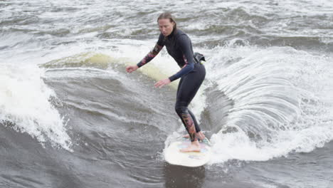 woman athlete - surfing on a river wave