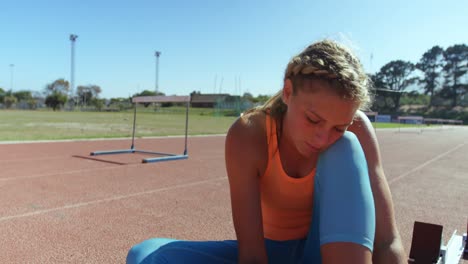 Vista-Frontal-De-Una-Atleta-Caucásica-Atando-Cordones-De-Zapatos-En-Un-Recinto-Deportivo-4k