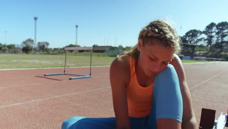vista frontal de una atleta caucásica atando cordones de zapatos en un lugar deportivo 4k