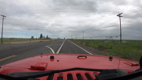 Conduciendo-Un-Vehículo-Rojo-En-La-Carretera-17-Con-Granjas-A-La-Derecha-Y-A-La-Izquierda