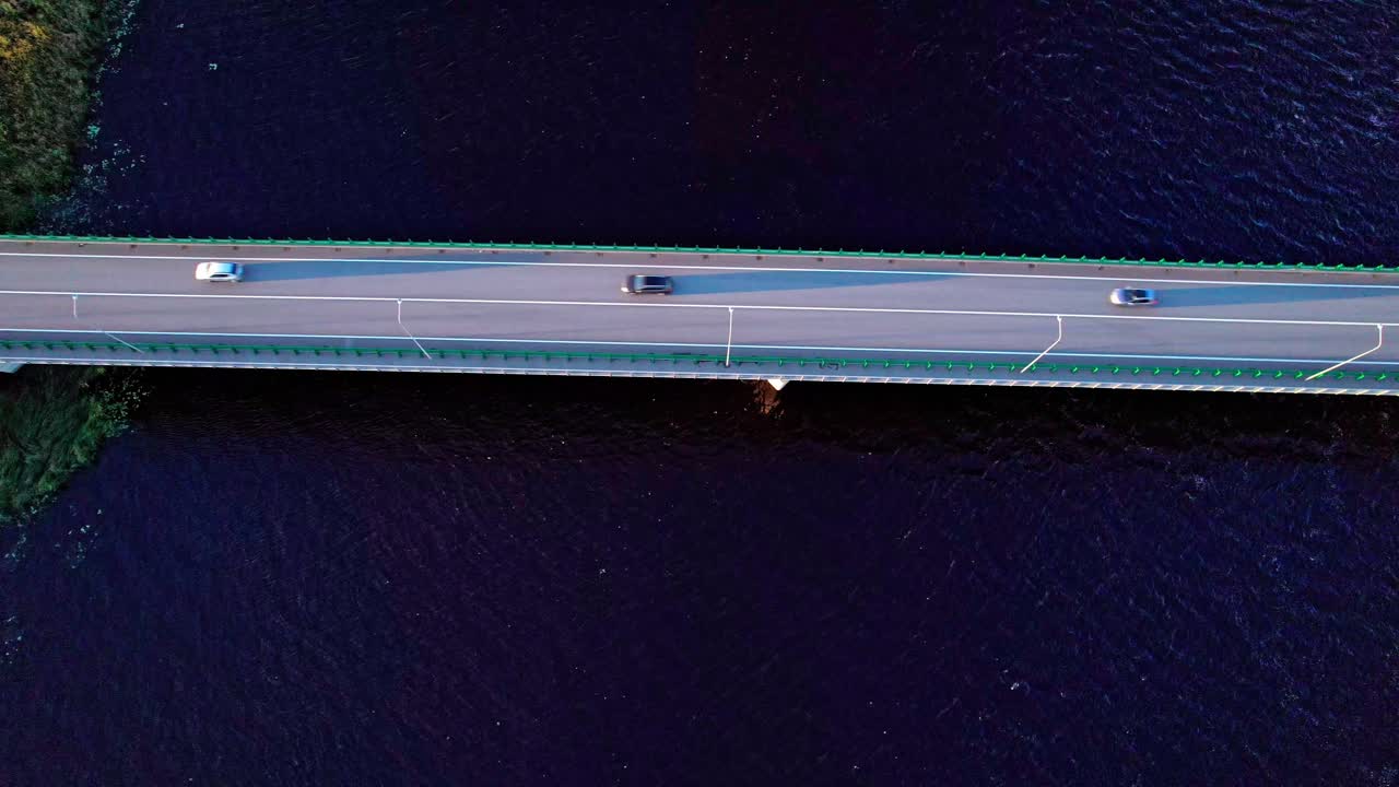 Cars driving on a bridge over water in Latvia at sunset