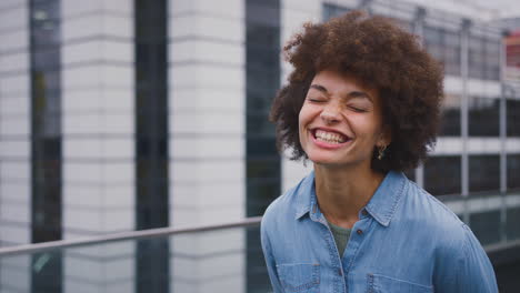 portrait of smiling young businesswoman standing outside modern office